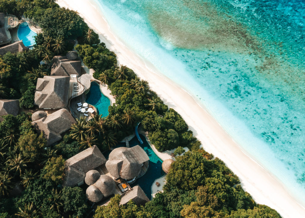 Aerial view showing luxury villas near the ocean and surrounded with thick vegetation.