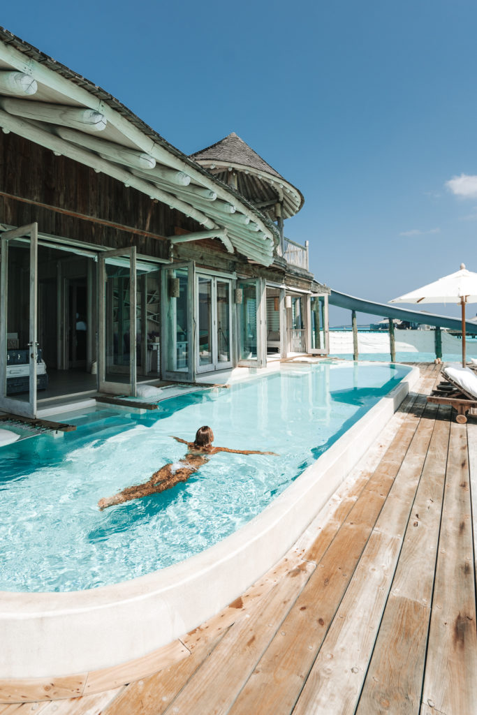 Woman swims in pool of her luxury villa.