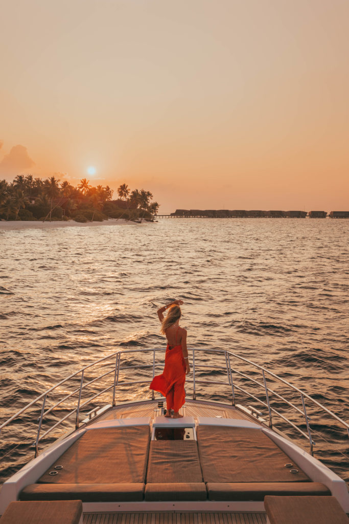 Woman looking into the sunset at the front of a luxury boat.
