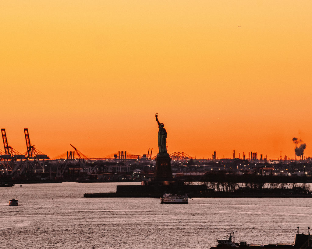 Vibrant sunset over the river, with Statue of Liberty silhouetted
