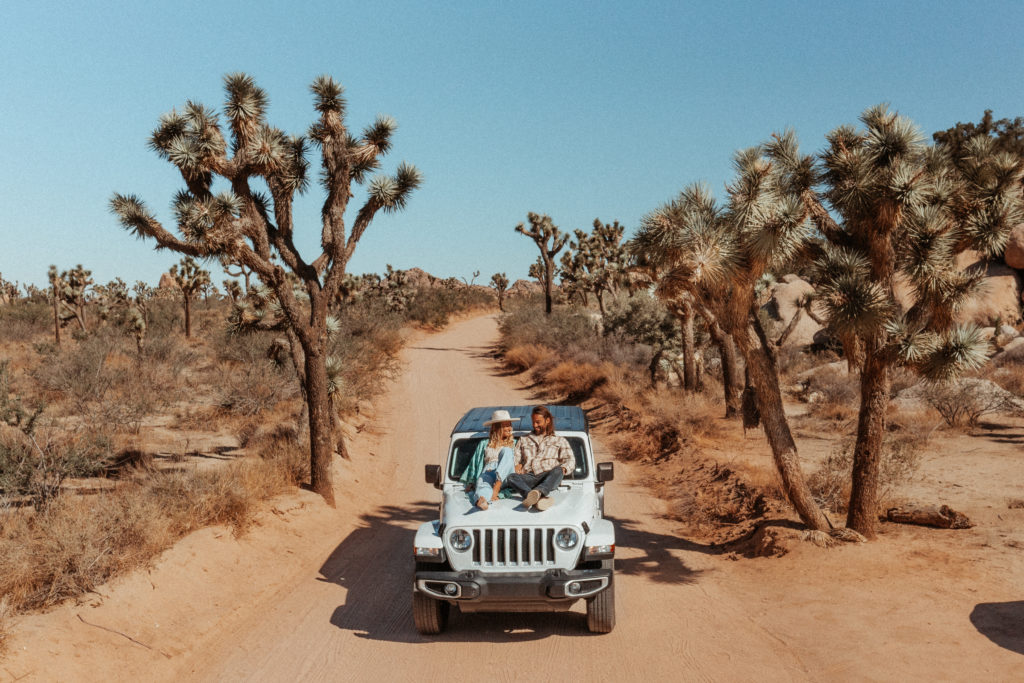 Sez and Chesh sitting on top of a Jeep in Joshua Tree