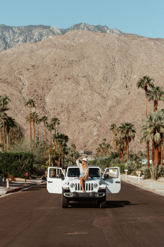 Sarah sitting on a Jeep in Palm Springs with mountains beyond