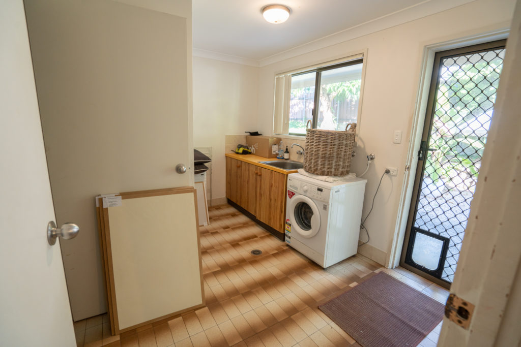 Laundry in original condition with separate toilet, brown awful tiles, cream walls.