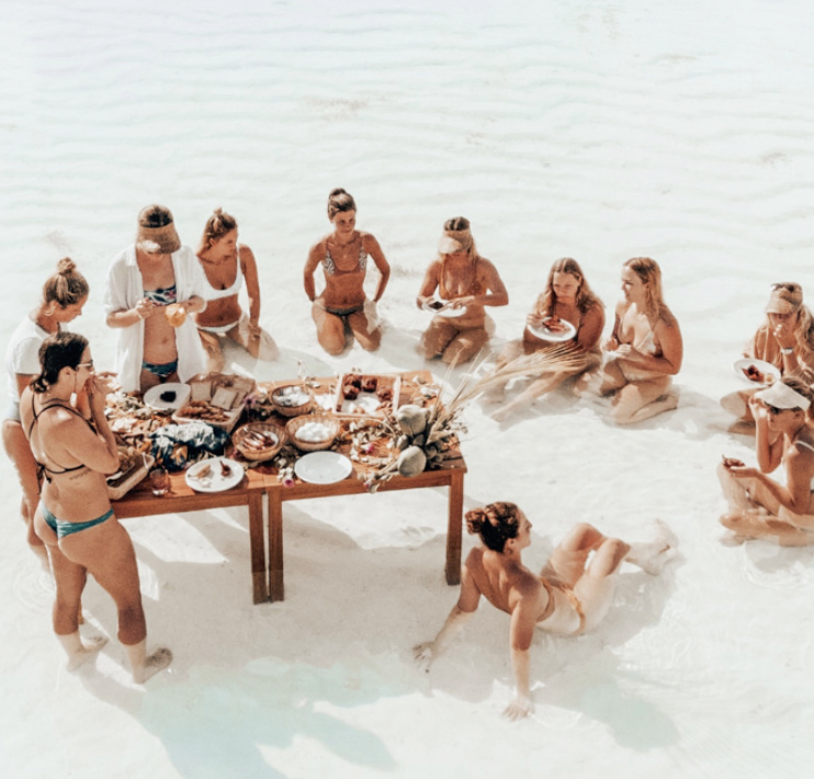 Group of girls having breakfast in the shallow waters in Maldives