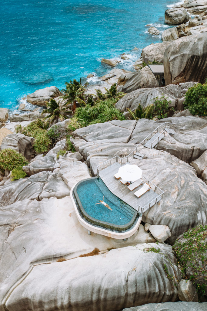 Woman floating in pool at Six Senses resort, surrounded by granite boulders and overlooking the ocean.