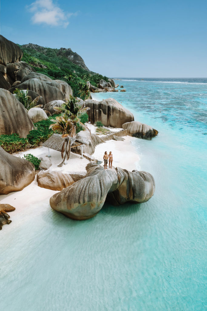 Couple standing on a granite boulder at famous beach in Seychelles