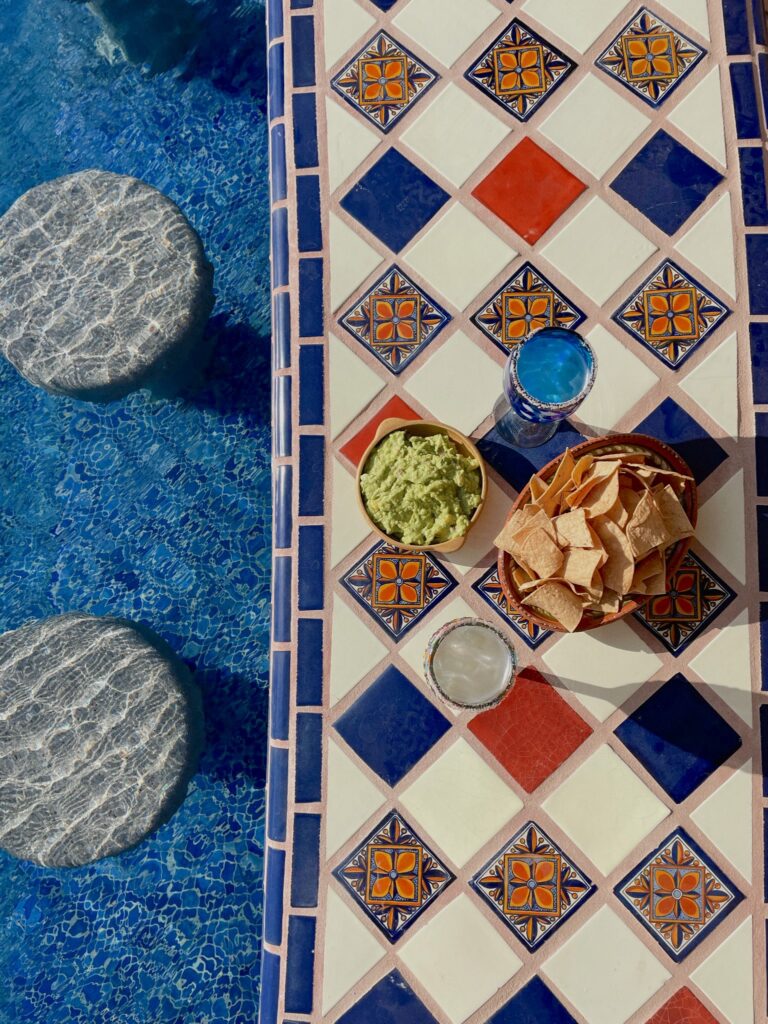 Guacamole and chips set on a colourful tiled bench top.