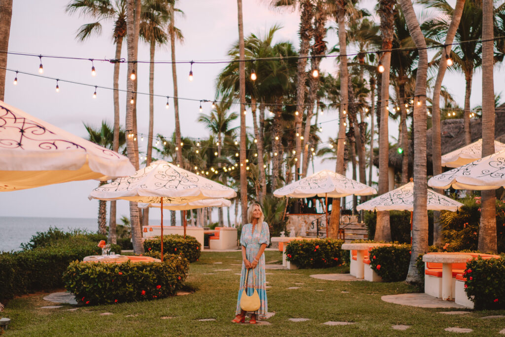 Woman in outdoor restaurant holding her handbag with fairy lights overhead, at Palmilla Hotel