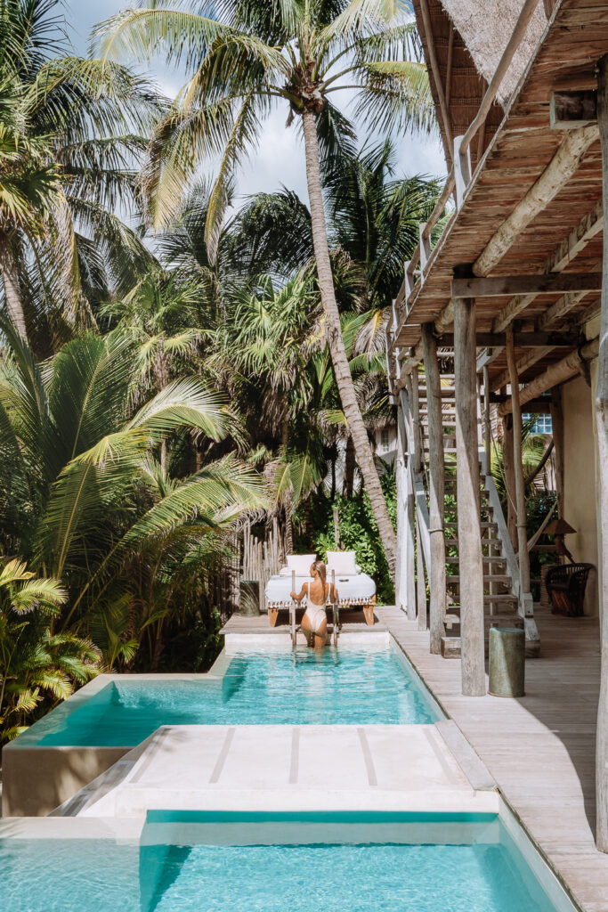 Woman exists small pool with a ladder and palm trees surrounding the pool area.