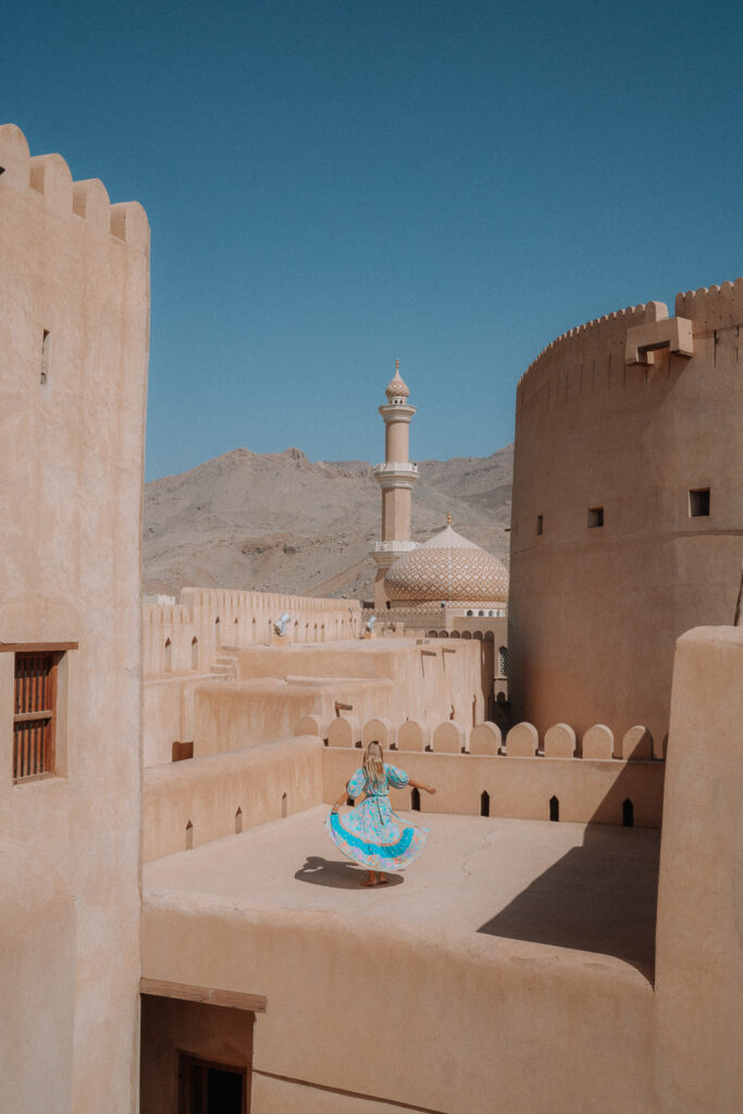 Woman in blue dress standing on rooftop of Nizwa Fort