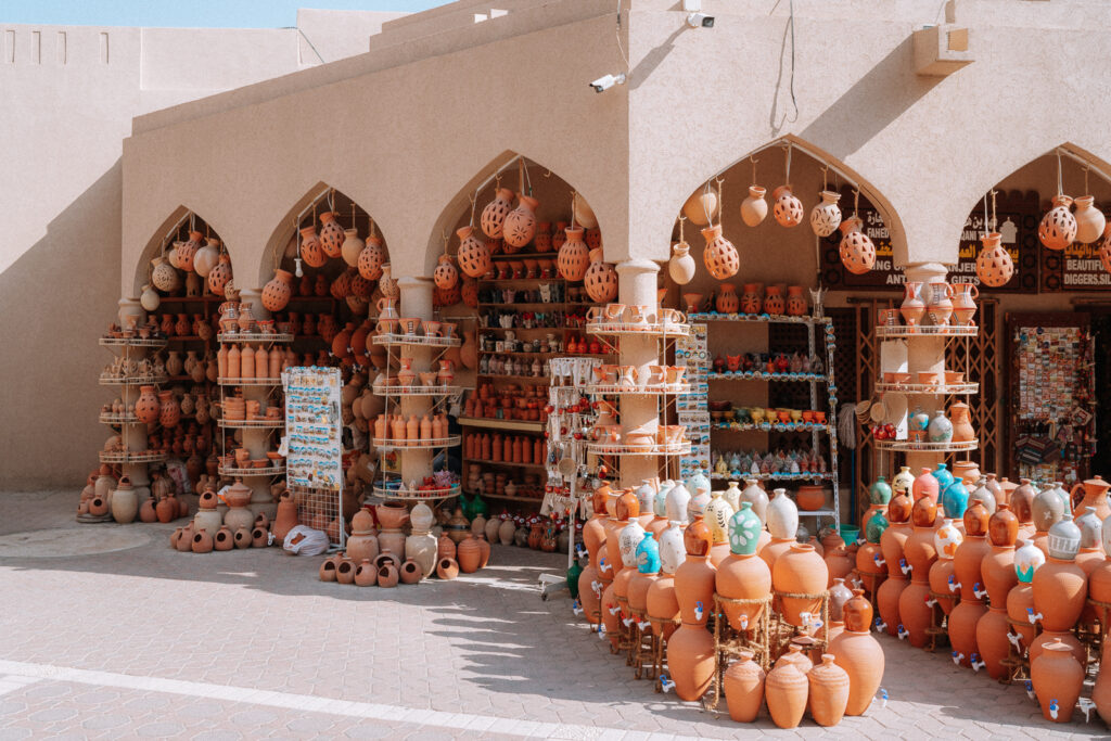Ceramic shop in Nizwa Souq with vases stacked on the ground and hanging from the archways.