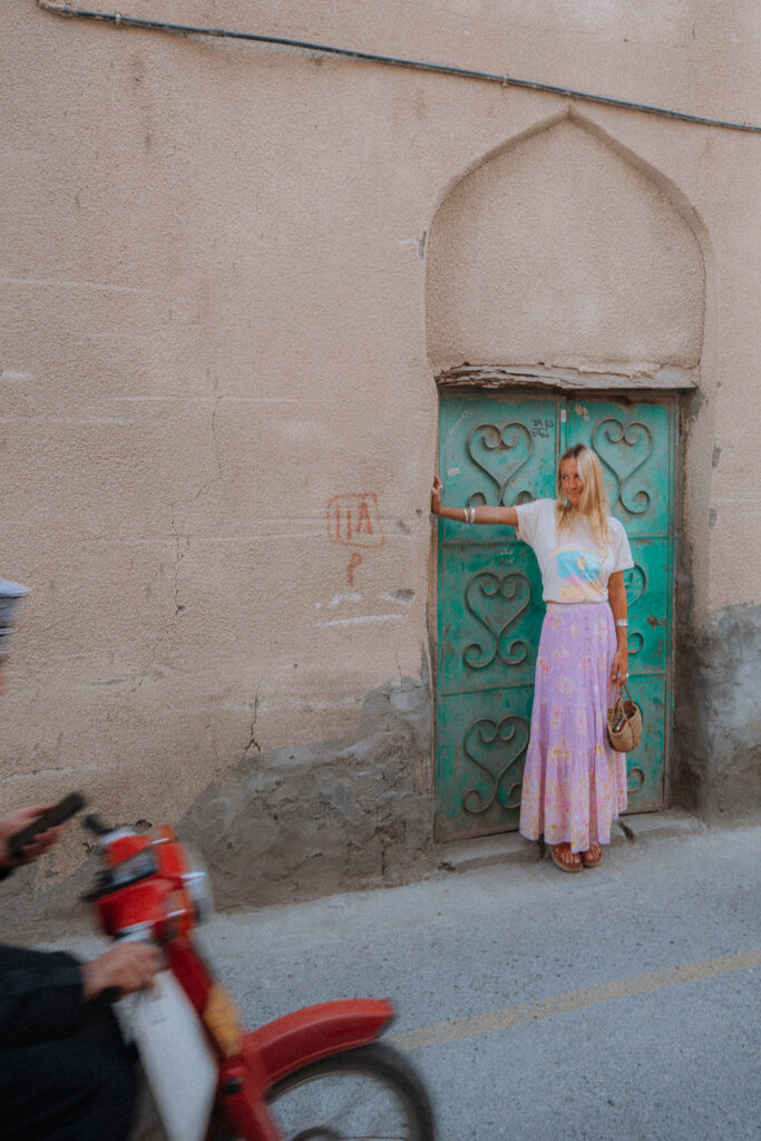 Woman stands in doorway in Nizwa old town.
