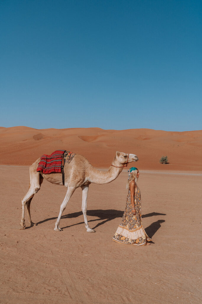 Woman walking with a camel in the desert