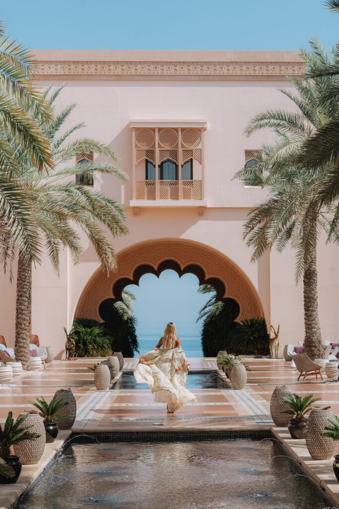 Woman walks towards an archway in the courtyard of the Shangri-La Al Husn