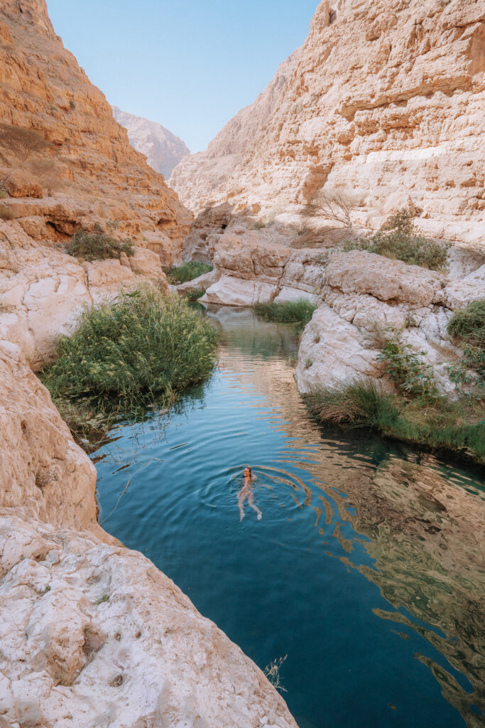 Woman smiles and swims into a wadi swimming pool.