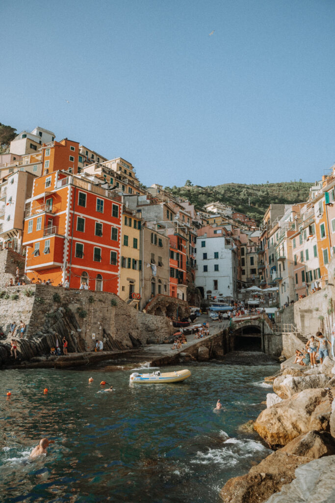 Harbour of Riomaggiore in the foreground, with the village of bright coloured buildings above.