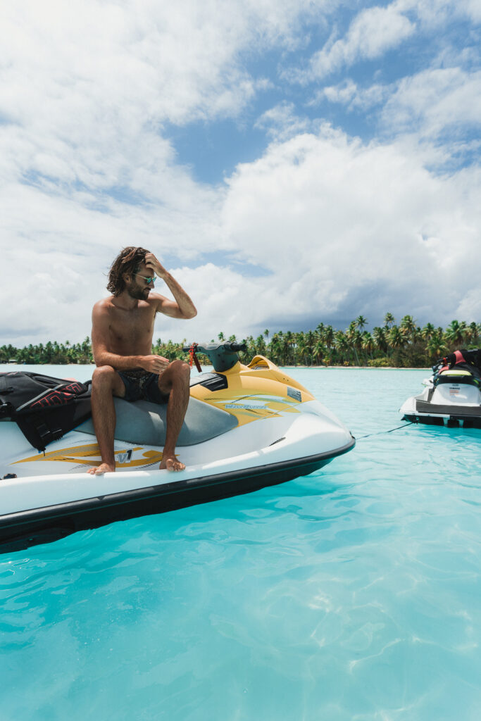 Man sitting on JetSki, parked in an inlet of the Bora Bora lagoon with urquoise blue water
