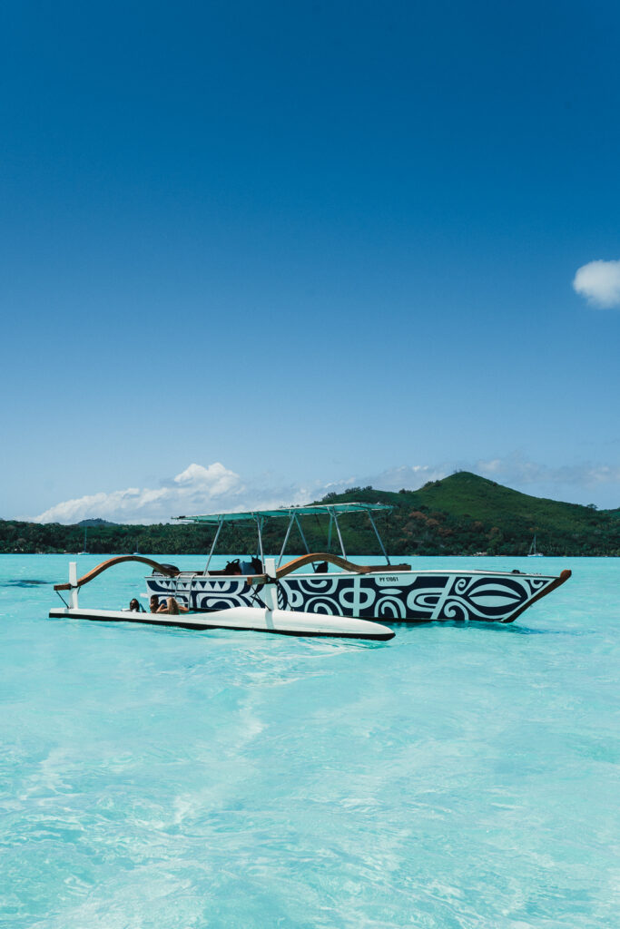 One of the tour boats in Bora Bora, floating in shallow lagoon water.