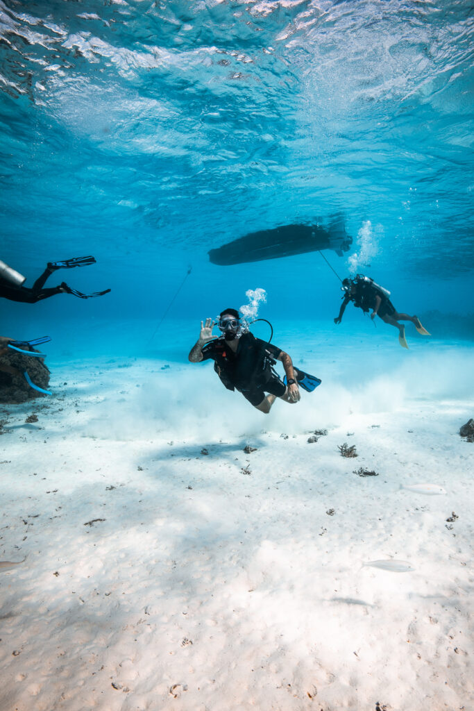 Beginner diver waving at the camera underwater while scuba diving in Bora Bora