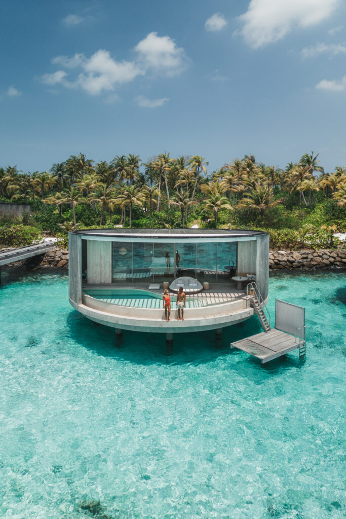 Man and woman stand on the edge of an overwater villa in Maldives.