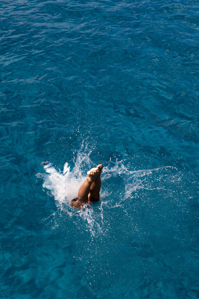 Person diving into water, with only legs visible above water