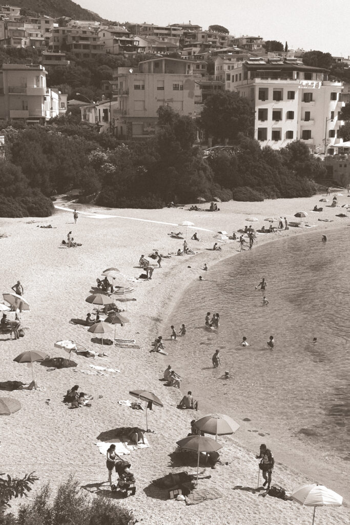 Black and white photo of beach umbrellas and bathers at a beach in Cala Gonome.