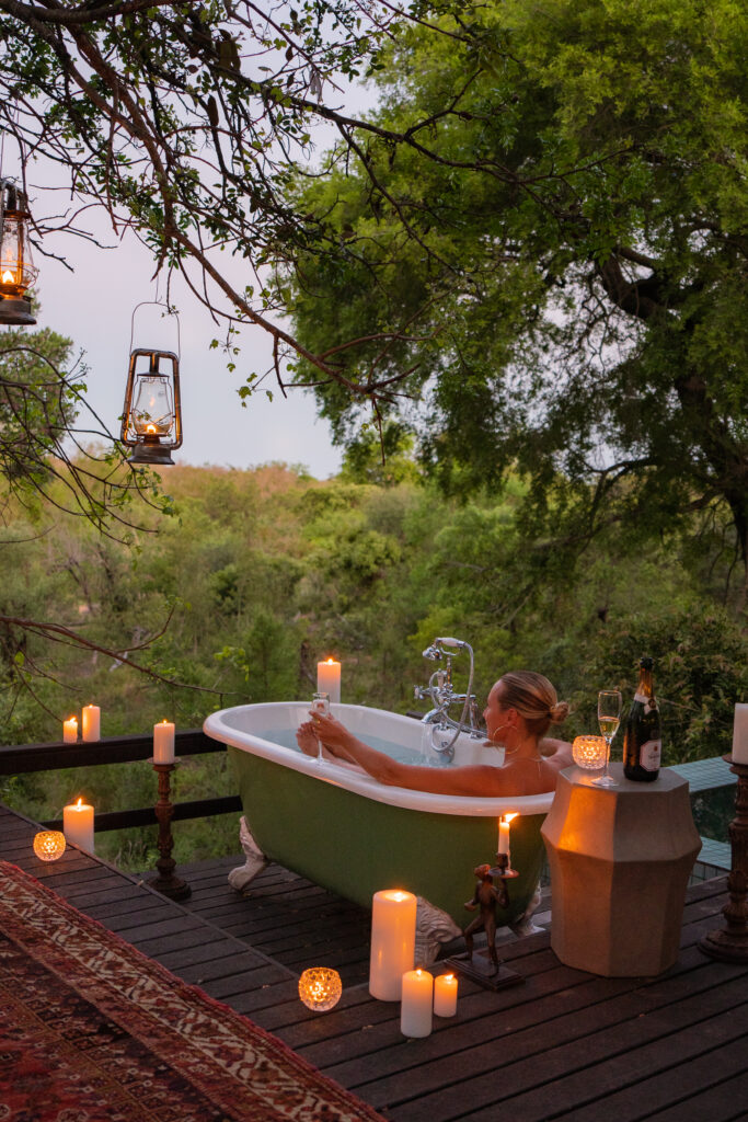 salty luxe sitting in a bathtub at royal malewane south africa with lit candles surrounding her