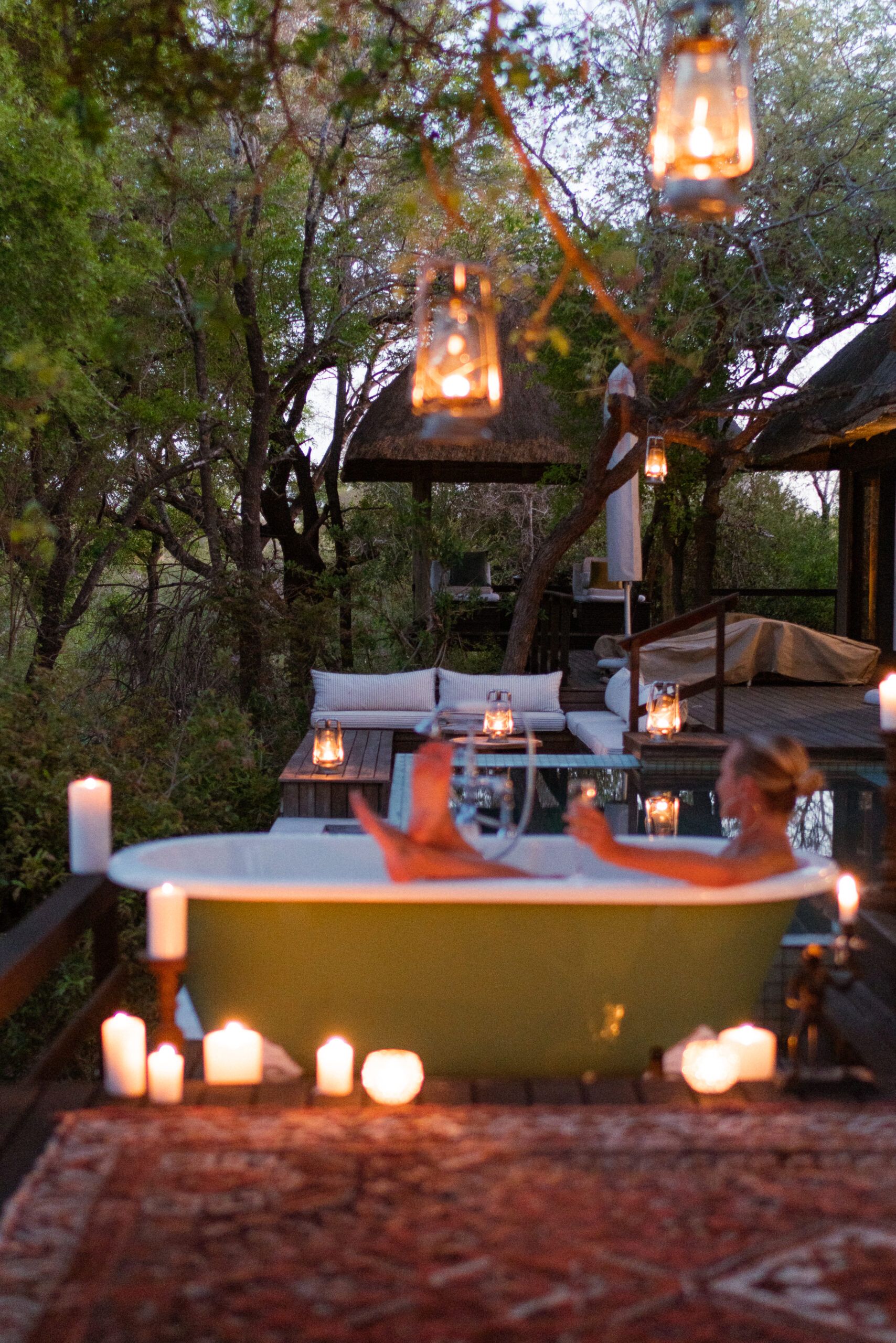 salty luxe in a bathtub surrounded by candles at dusk at malewane lodge south africa