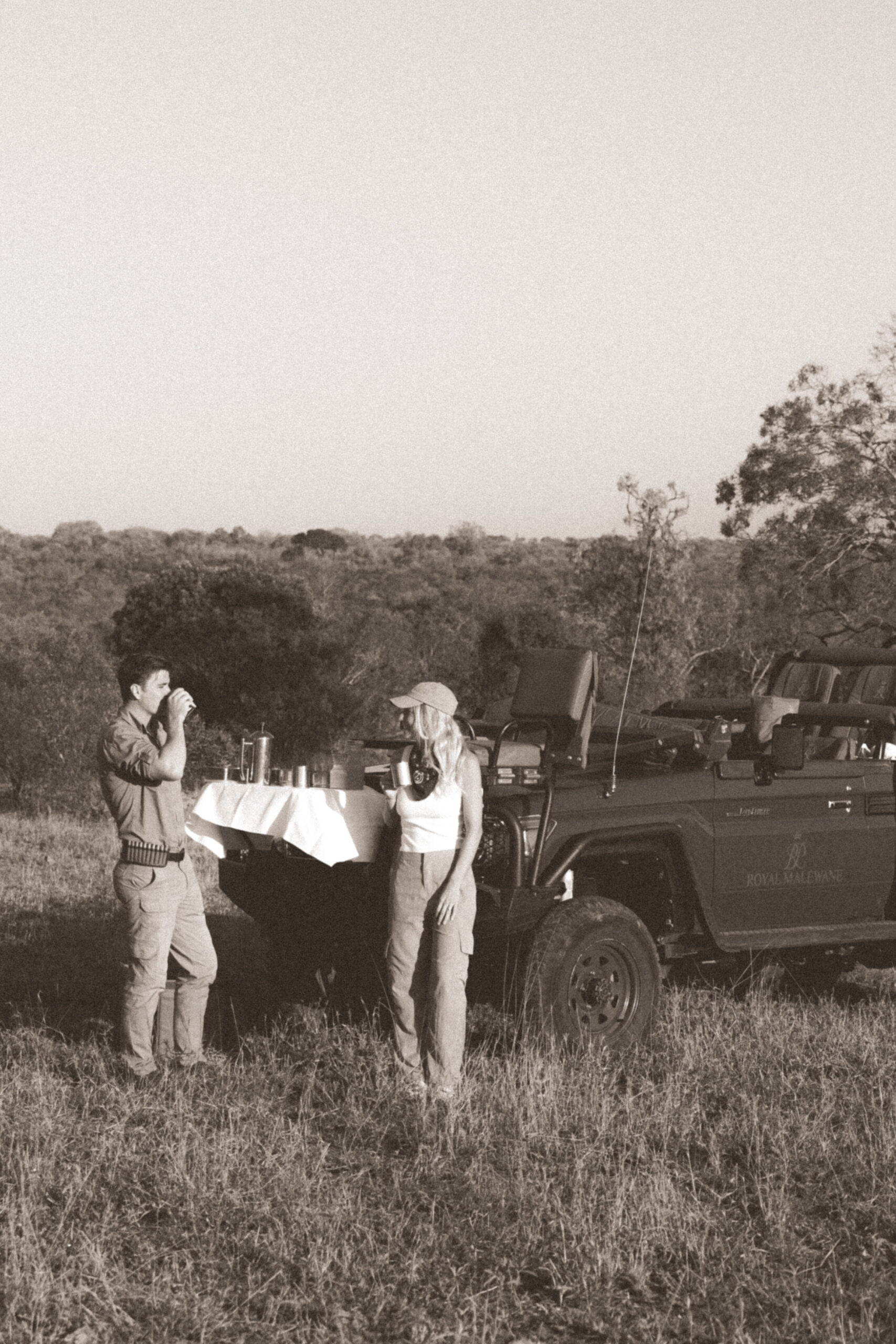 black and white photo of couple enjoying drinks on a safari vehicle in kruger national park