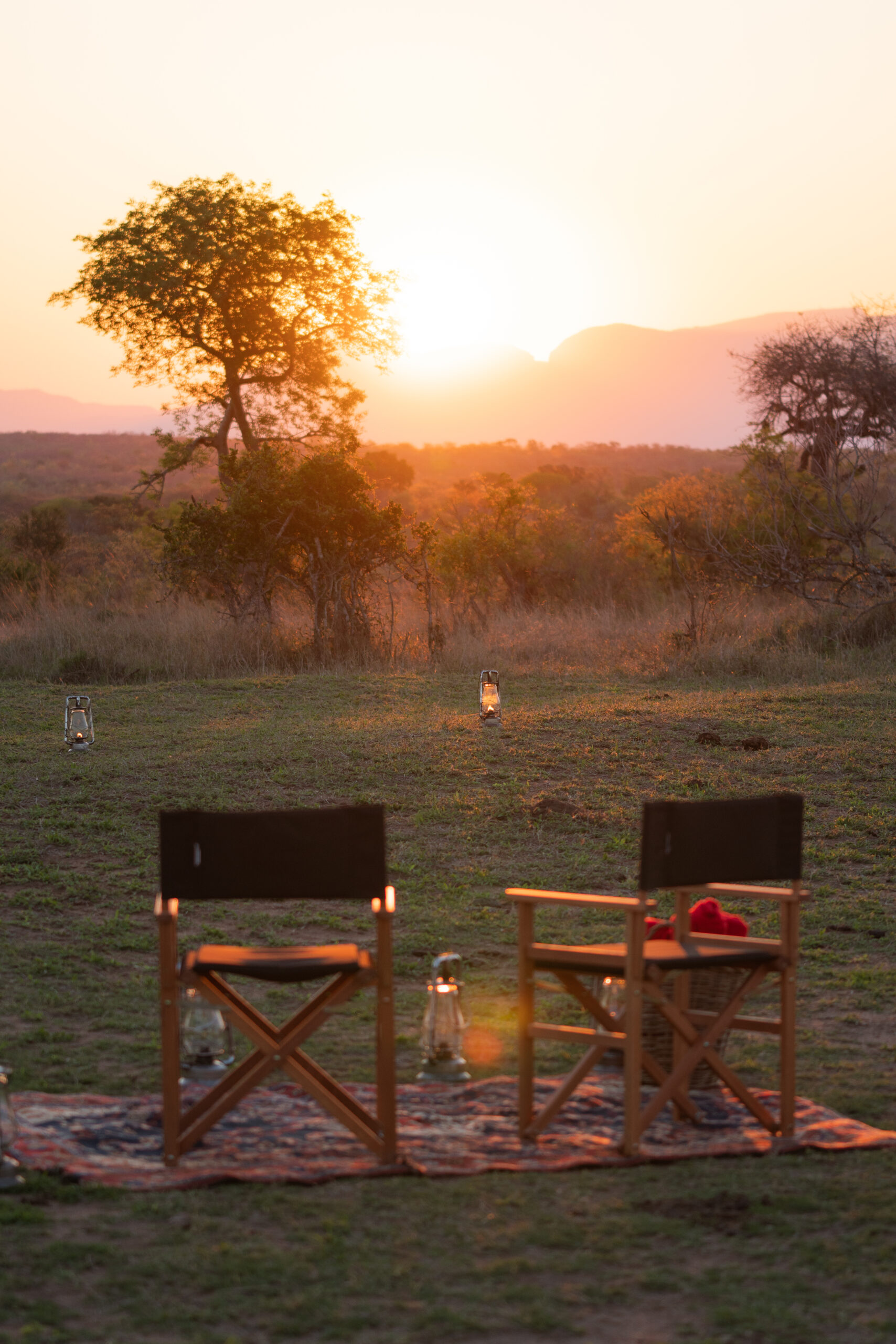 sunset in kruger national park with two chairs set up on a rug