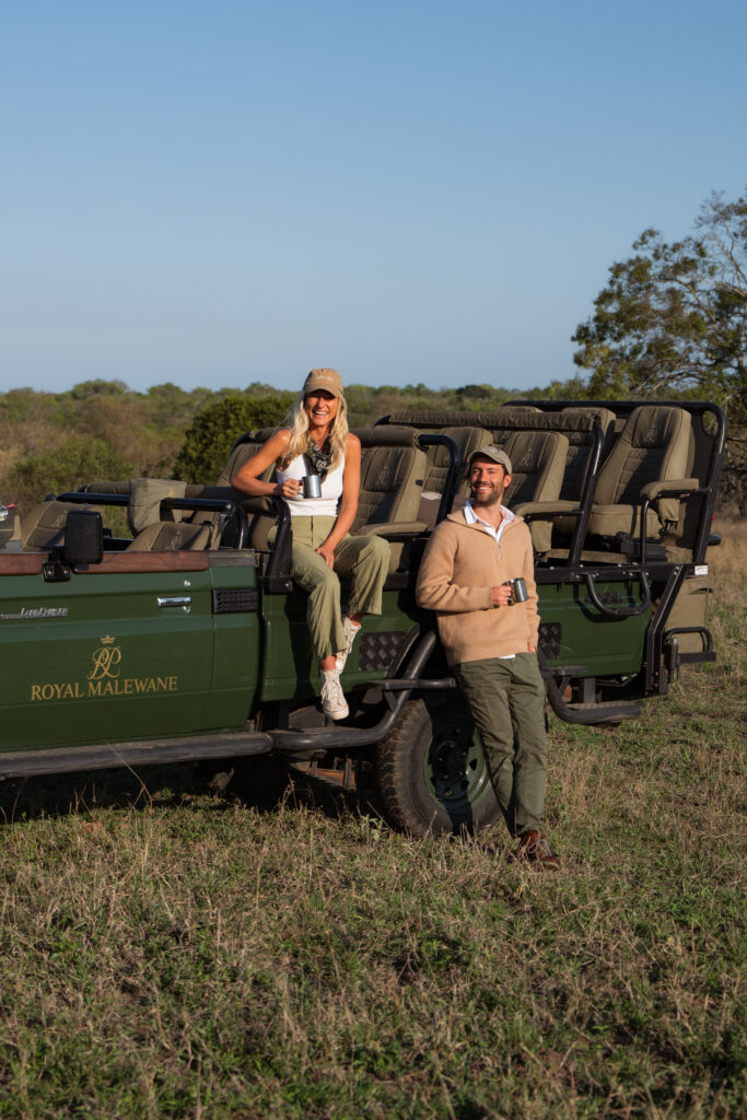 a couple sitting on the side of a royal malewane safari vehicle