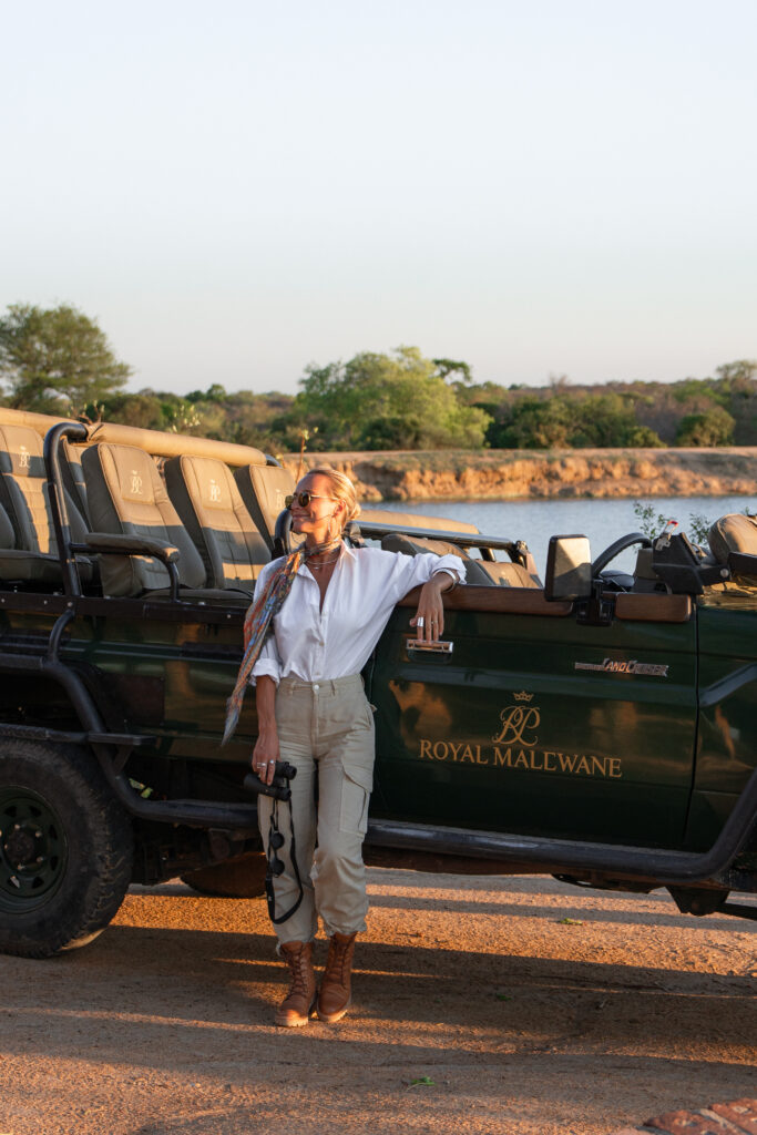 salty luxe holding binoculars and leaning on a royal malewane safari vehicle