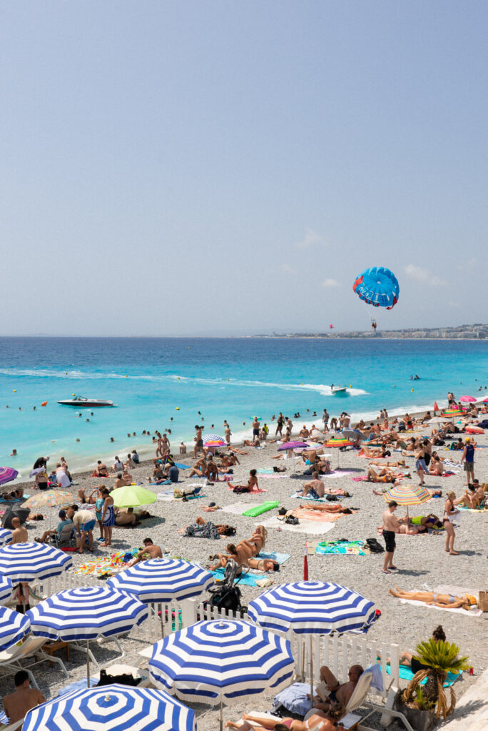 beach in nice france with parasailing and people on the beach and boats in the water