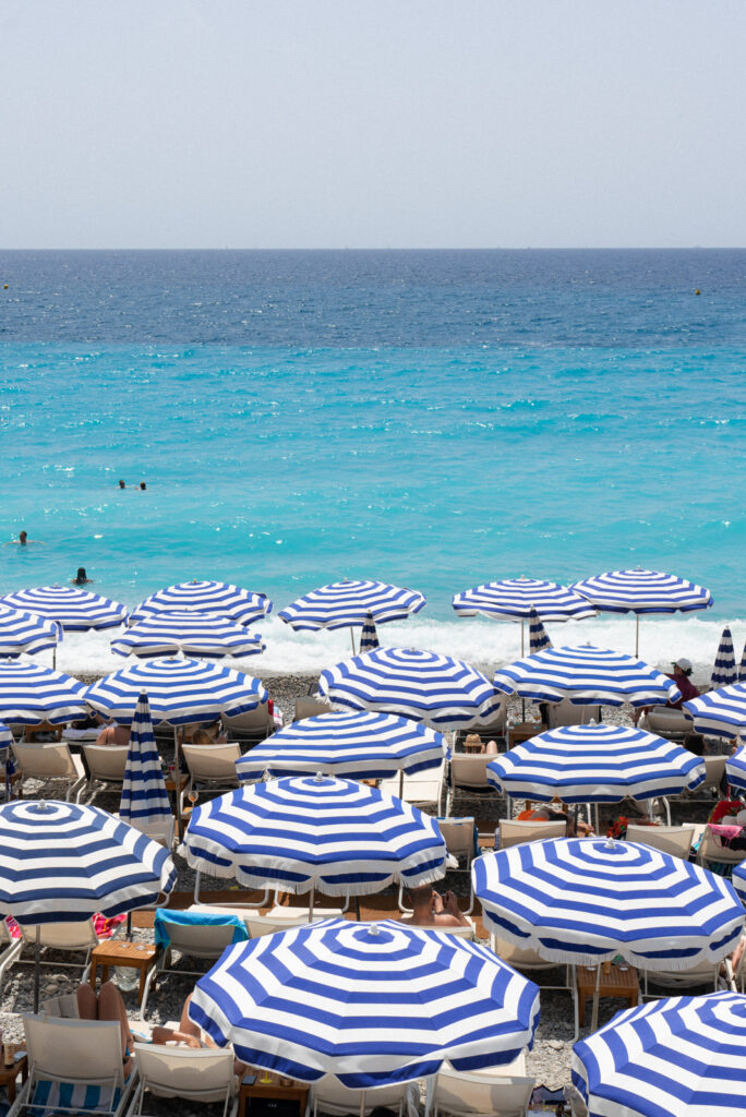 blue and white beach umbrellas on a beach in nice france