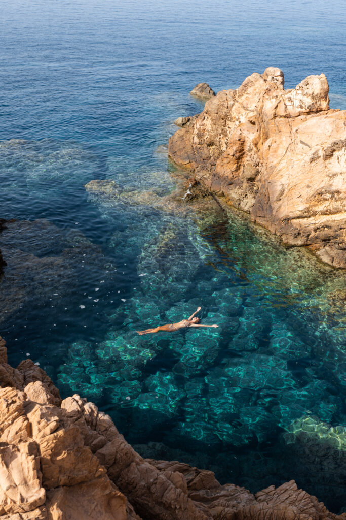 A woman floating in the water at Cala Pregonda, one of the best beaches in Menorca