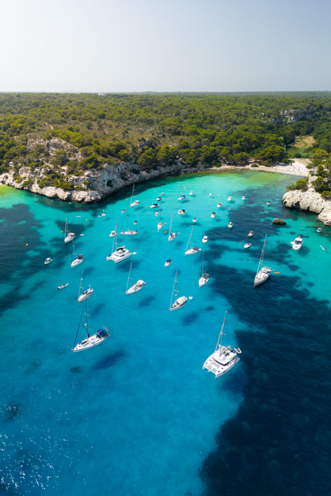 boats float in the sparkling blue water at cala macarelleta