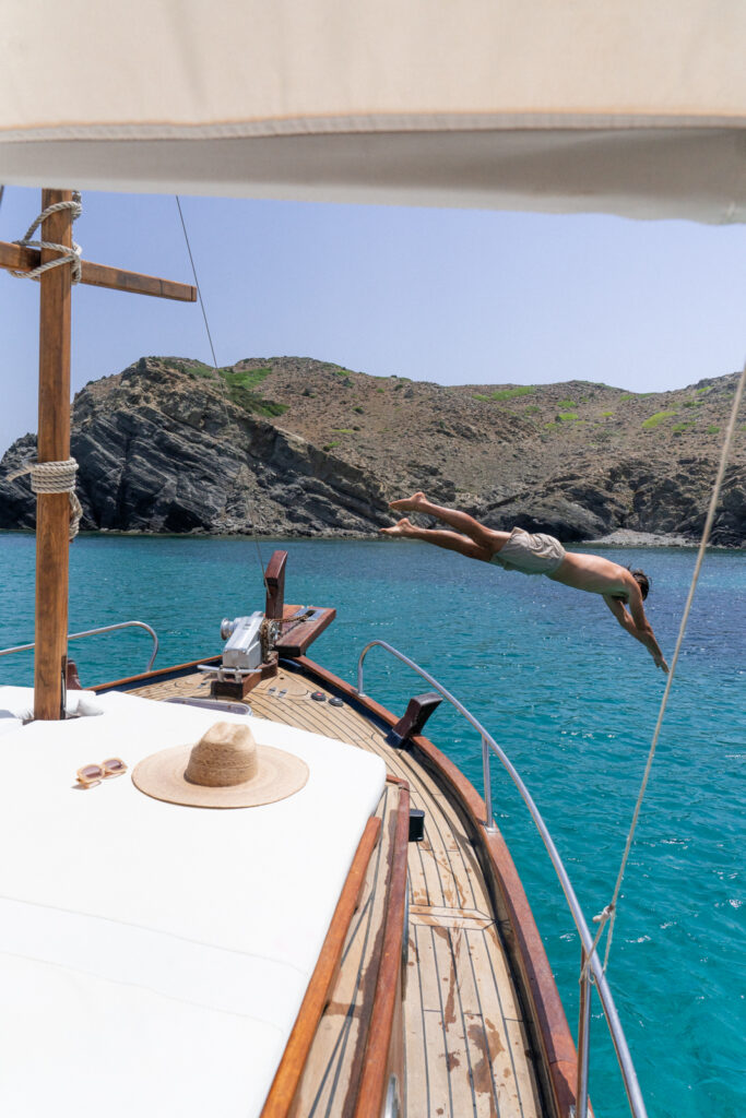 Man jumping into the water from a boat tour, one of the top things to do in Menorca Spain