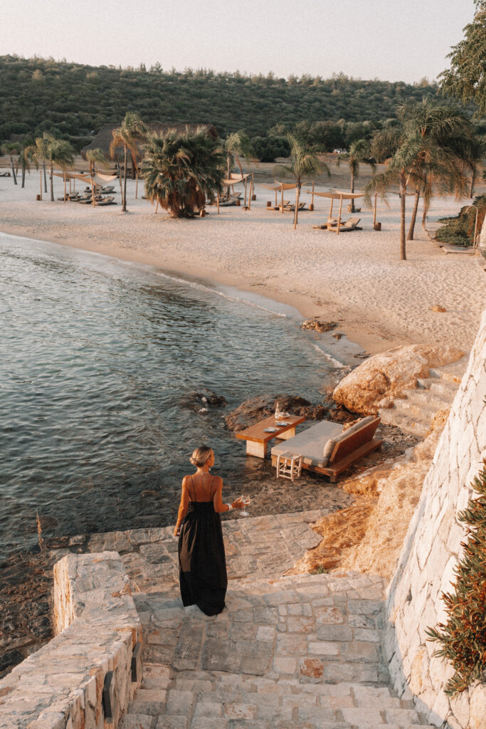 salty luxe walking down a stone staircase to the beach in a black dress at Six Senses Kaplankaya