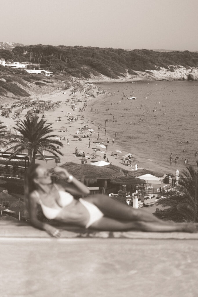 Woman laying on edge of pool overlooking the beach at Villa le Blanc Gran Melia Menorca