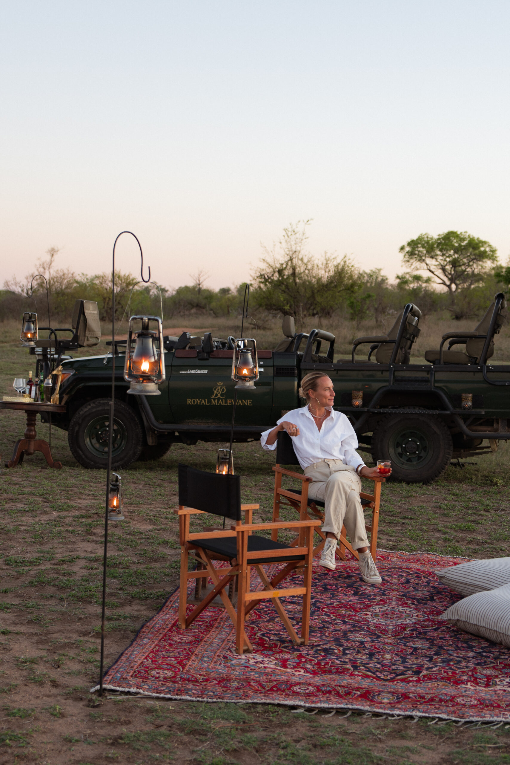 Salty Luxe enjoying a sunset drink in Kruger National Park with Royal Malewane setup and vehicle