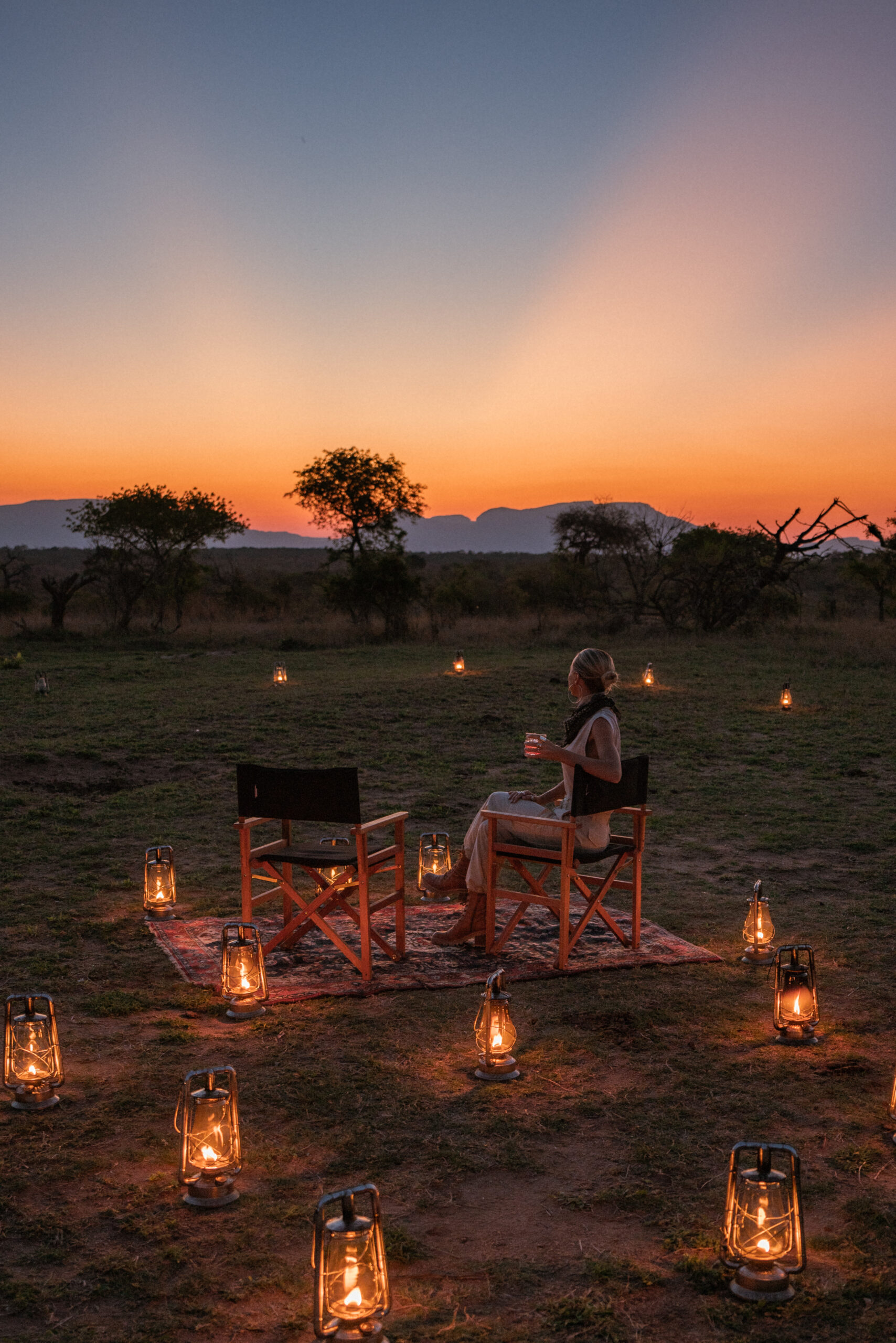 lantern lit sunset dinner in kruger national park where salty luxe sits with a sunset drink