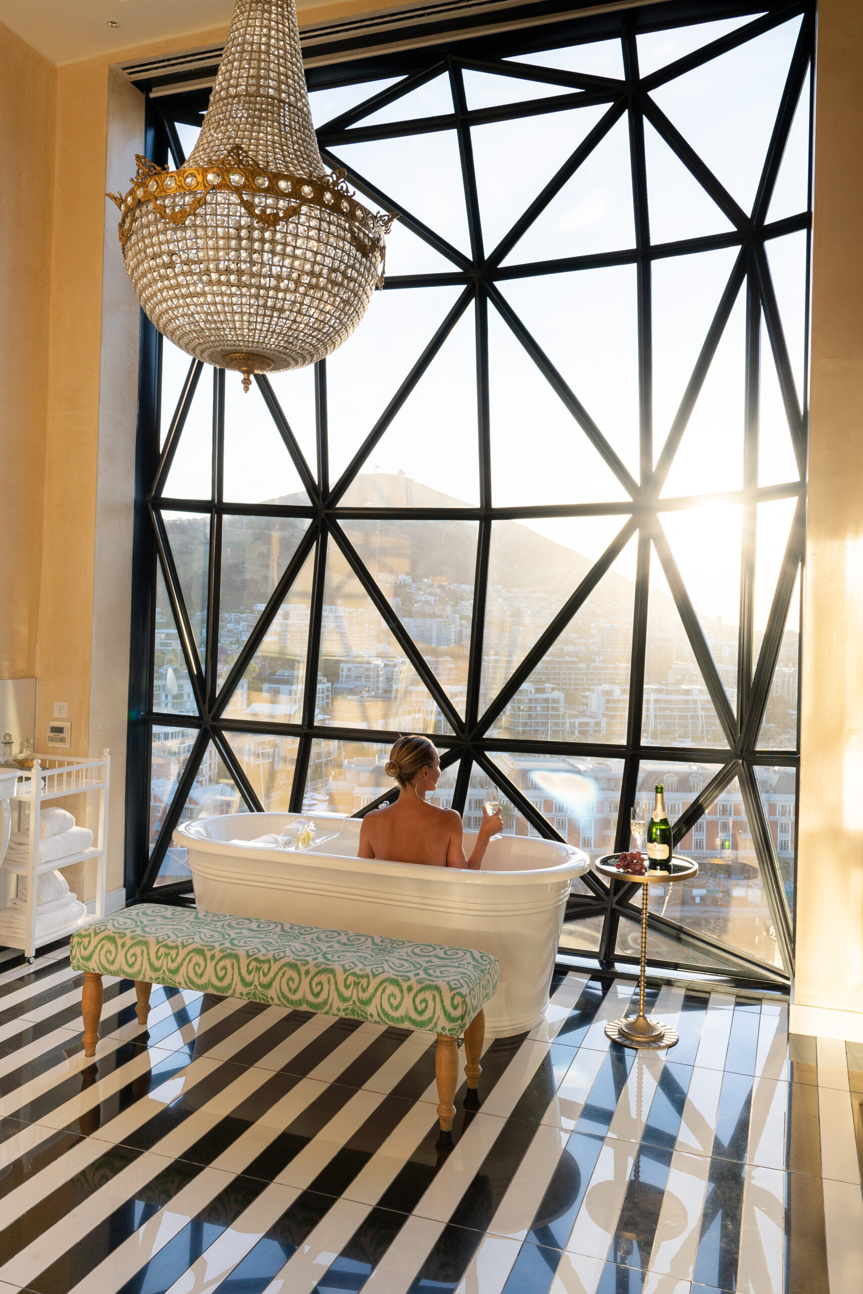 salty luxe in a bathtub at the silo hotel cape down looking out the window with a glass of champagne