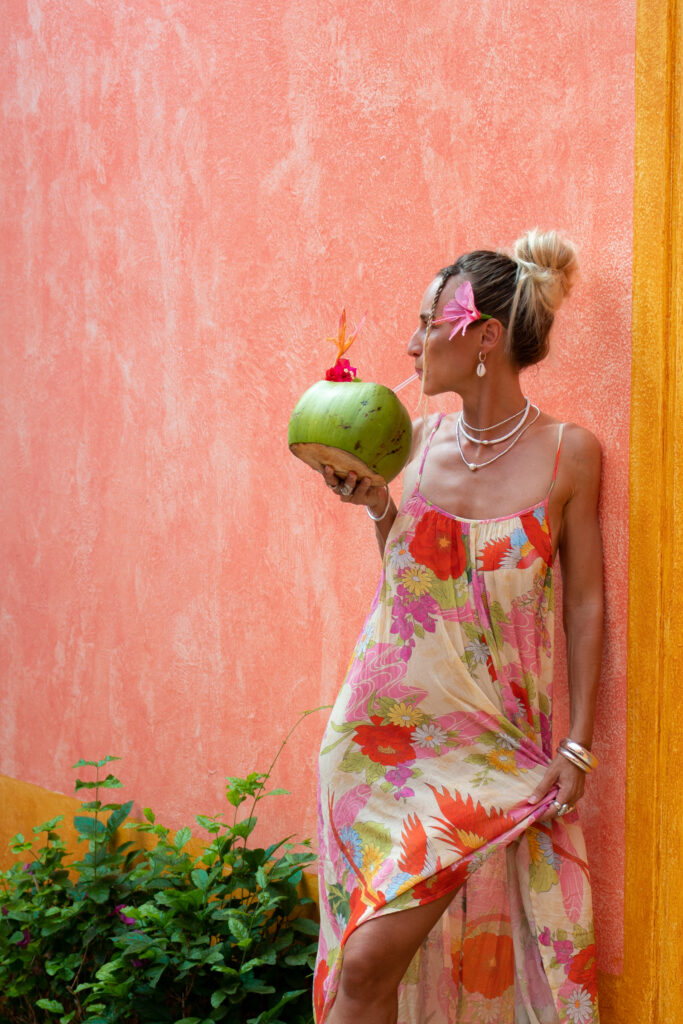 salty luxe drinking a coconut in a floral dress at las alamandas hotel