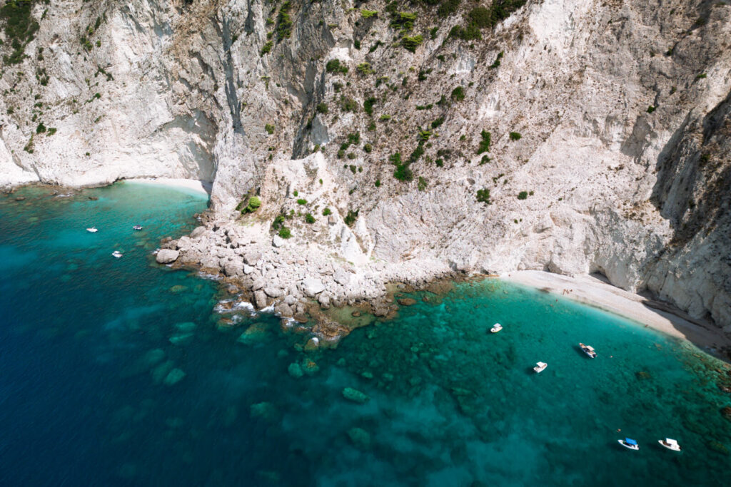 drone shot of boats at paradise beach in corfu greece