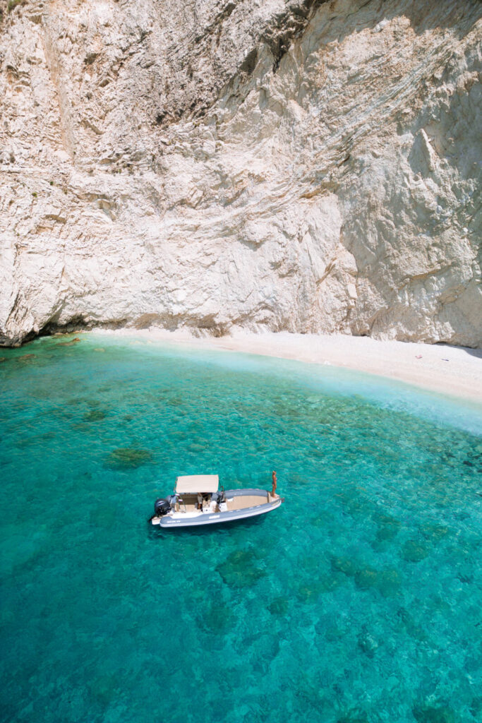 boat in clear blue waters of Corfu at Paradise Beach